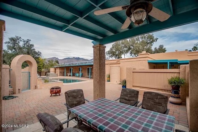 view of patio with a fenced in pool, a mountain view, and ceiling fan