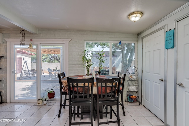 dining area featuring light tile patterned floors and lofted ceiling with beams