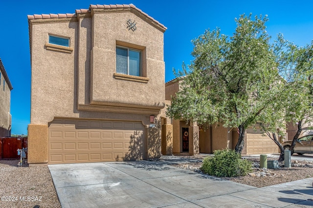 view of front of house featuring stucco siding, an attached garage, a tile roof, and driveway