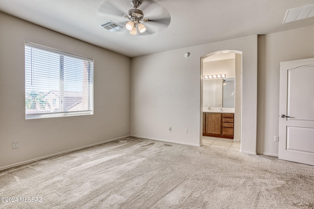 unfurnished bedroom with ceiling fan, light carpet, and ensuite bath