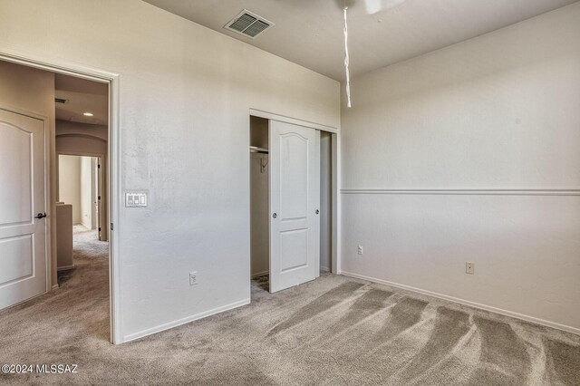 unfurnished bedroom with a closet and light carpet