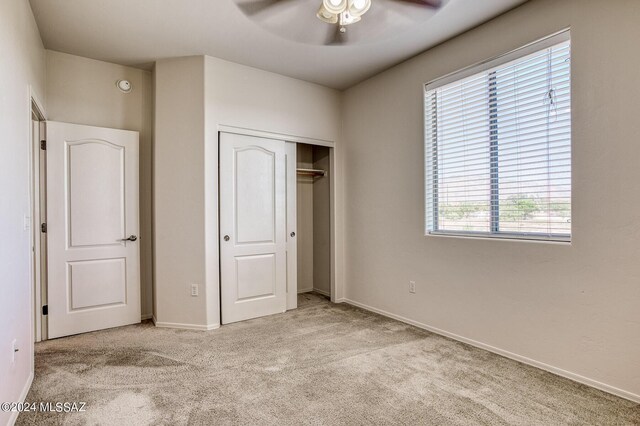 unfurnished bedroom with ceiling fan, light colored carpet, a closet, and multiple windows