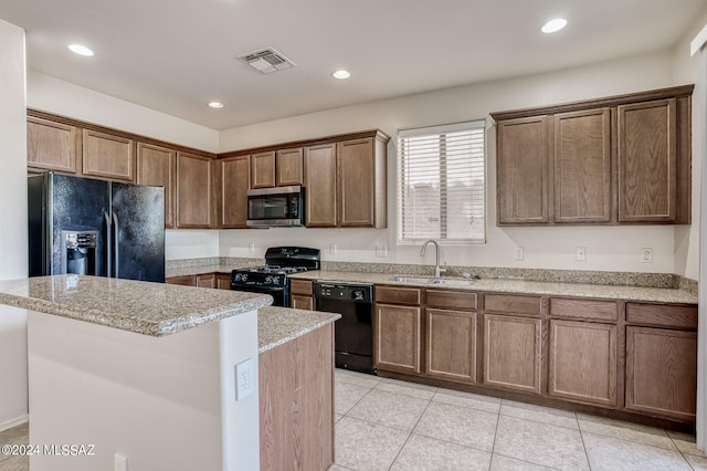 kitchen with light stone counters, light tile patterned flooring, sink, a kitchen island, and black appliances