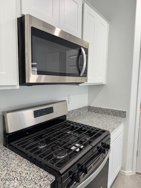 kitchen with appliances with stainless steel finishes, white cabinetry, and light stone countertops