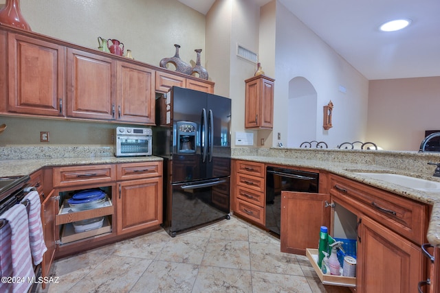 kitchen featuring black appliances, light stone countertops, sink, and vaulted ceiling