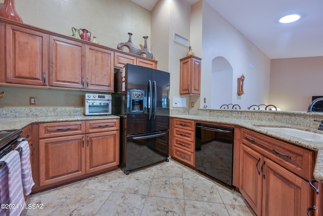 kitchen with light stone countertops, sink, black appliances, and lofted ceiling