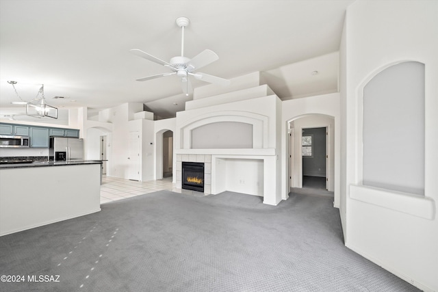 unfurnished living room featuring ceiling fan, a fireplace, and light carpet