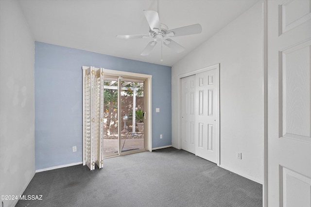 unfurnished bedroom featuring dark colored carpet, access to outside, vaulted ceiling, and ceiling fan