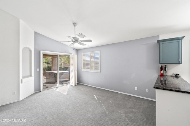 interior space with vaulted ceiling, dark carpet, and ceiling fan