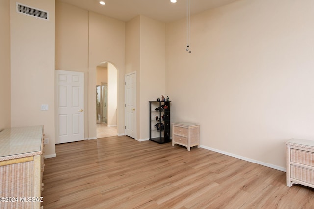 unfurnished room featuring light hardwood / wood-style floors and a towering ceiling