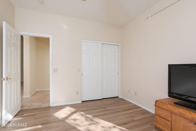 unfurnished bedroom with light wood-type flooring and a closet