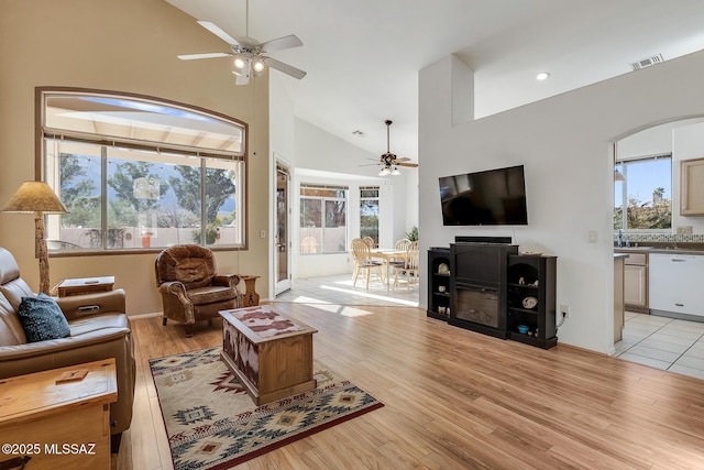 living room featuring ceiling fan, high vaulted ceiling, a wealth of natural light, and light hardwood / wood-style floors