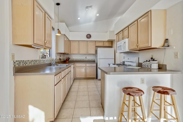 kitchen with sink, white appliances, hanging light fixtures, a kitchen breakfast bar, and light brown cabinetry