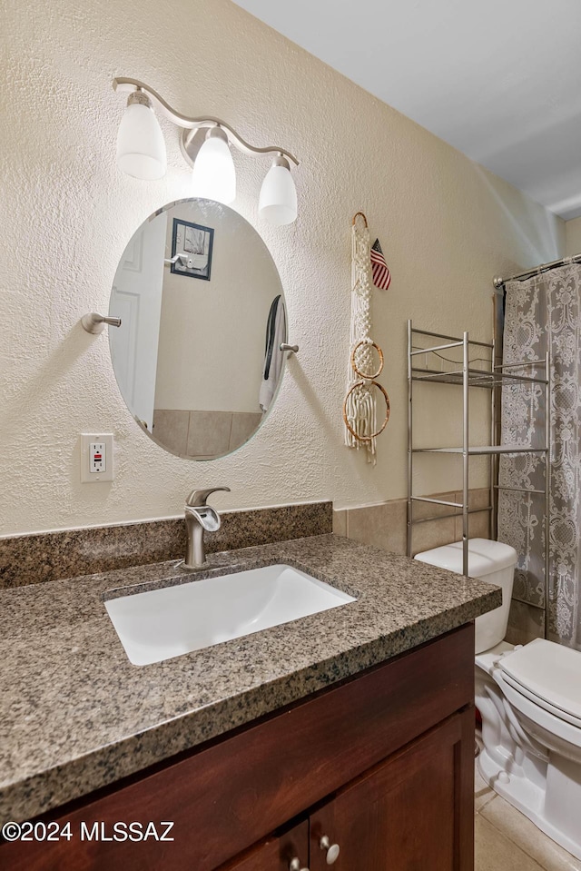 full bath featuring toilet, a textured wall, a shower with shower curtain, and vanity