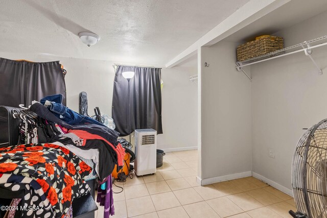 bedroom featuring a textured ceiling, baseboards, and tile patterned flooring