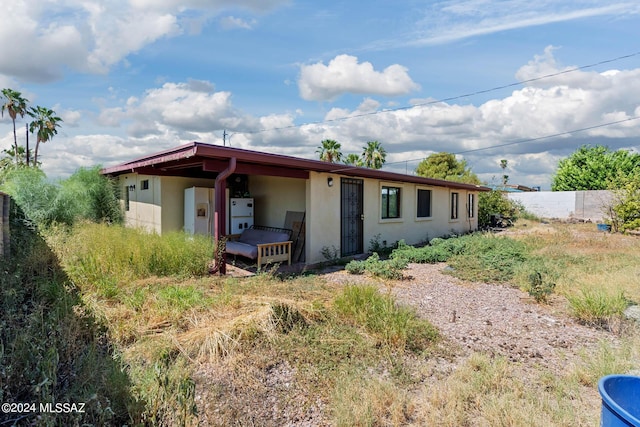 rear view of property featuring fence and stucco siding