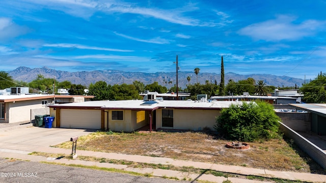 view of front of house featuring an attached garage, stucco siding, a mountain view, and driveway