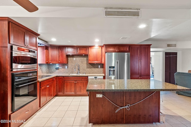 kitchen with a kitchen island, dark stone countertops, sink, and stainless steel fridge