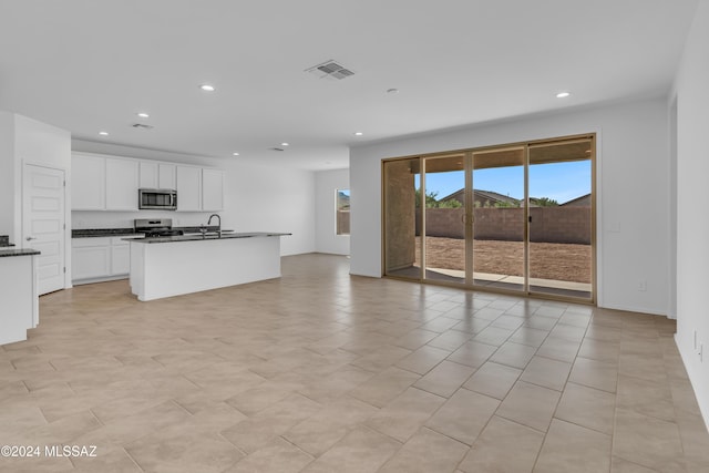 kitchen with a kitchen island with sink, sink, light tile patterned floors, white cabinetry, and stainless steel appliances