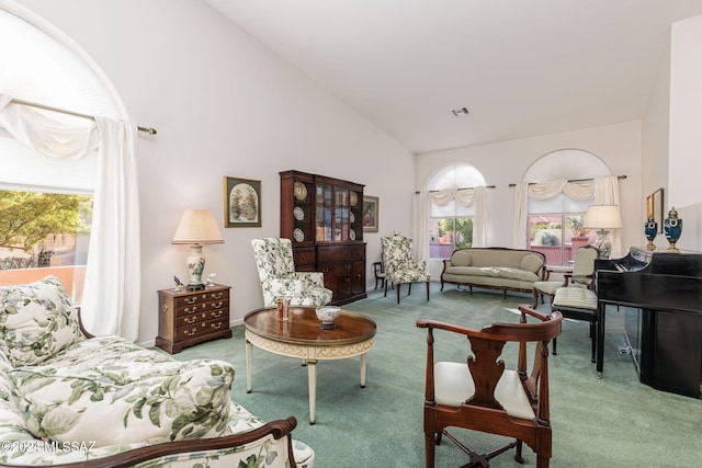 carpeted living room with high vaulted ceiling