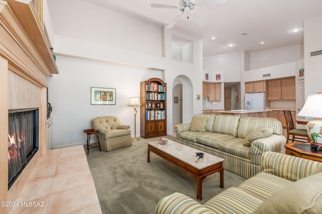 tiled living room with ceiling fan and a towering ceiling