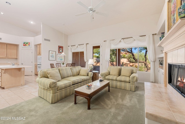 living room featuring a wealth of natural light, ceiling fan, light tile patterned floors, and a tile fireplace