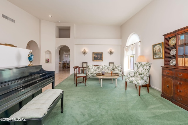 living area with carpet flooring and a towering ceiling