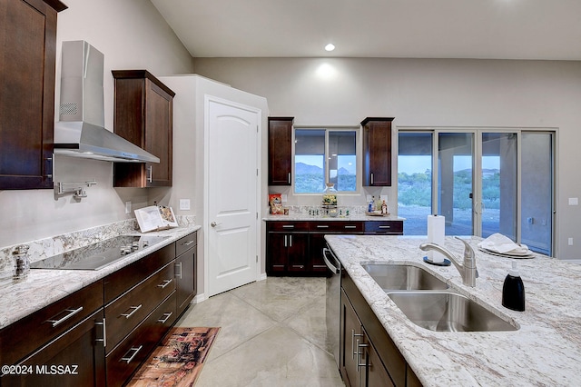 kitchen with wall chimney exhaust hood, black electric cooktop, light stone counters, and sink