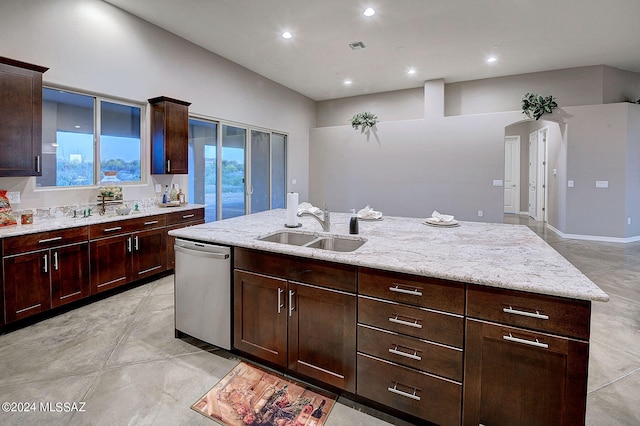 kitchen with a kitchen island with sink, dark brown cabinets, dishwasher, light stone counters, and sink