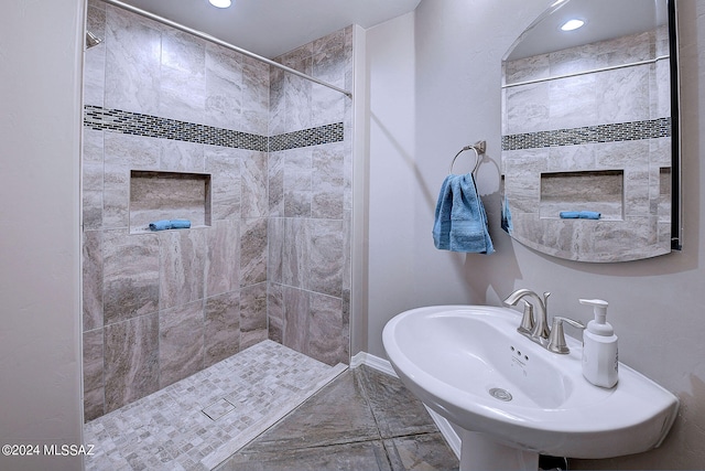 bathroom with tiled shower and sink