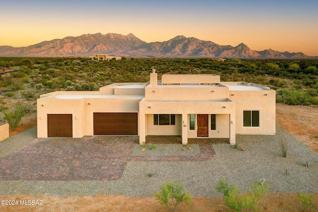 pueblo-style house featuring a garage and a mountain view