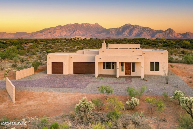 pueblo-style home featuring a garage and a mountain view