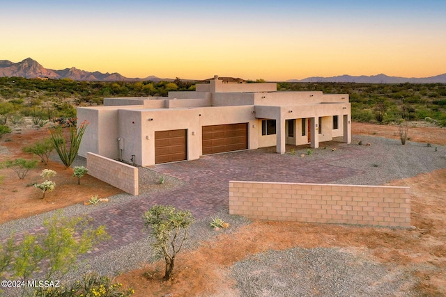 pueblo-style house featuring a garage and a mountain view