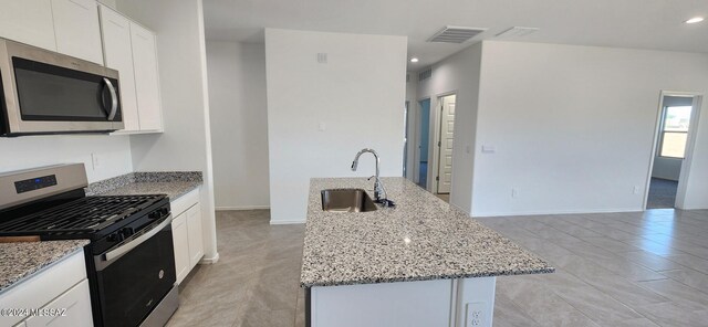 kitchen with light stone countertops, stainless steel appliances, white cabinetry, and sink