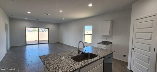 kitchen with stone counters, white cabinetry, an island with sink, sink, and black dishwasher