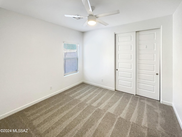 unfurnished bedroom featuring carpet flooring, visible vents, a ceiling fan, baseboards, and a closet