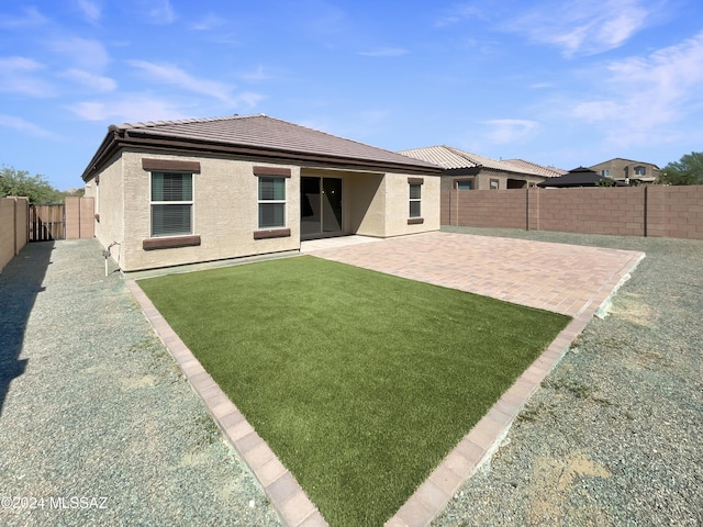 rear view of house with a lawn, a patio, a fenced backyard, a tiled roof, and stucco siding