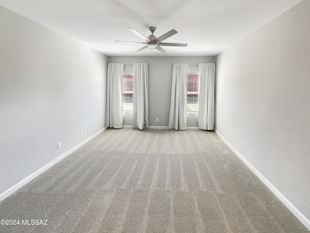 carpeted spare room featuring ceiling fan and baseboards