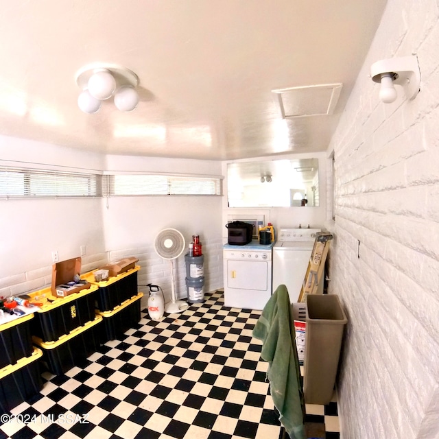 interior space with brick wall, washing machine and clothes dryer, and white cabinetry