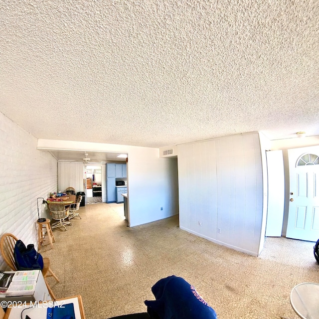 living room with brick wall and a textured ceiling