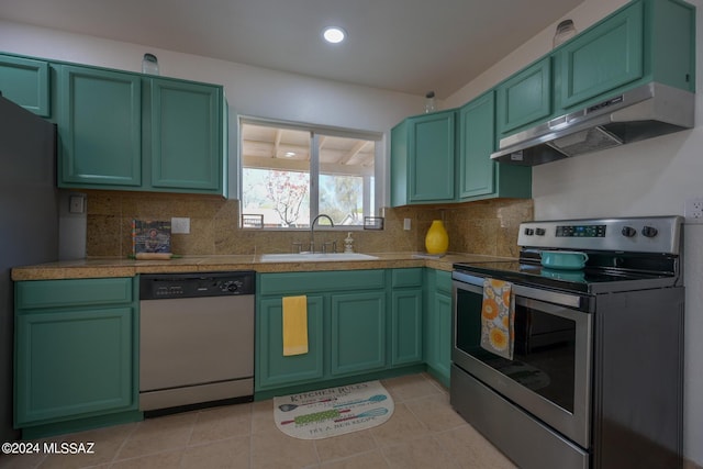 kitchen featuring sink, stainless steel appliances, backsplash, light tile patterned floors, and green cabinetry