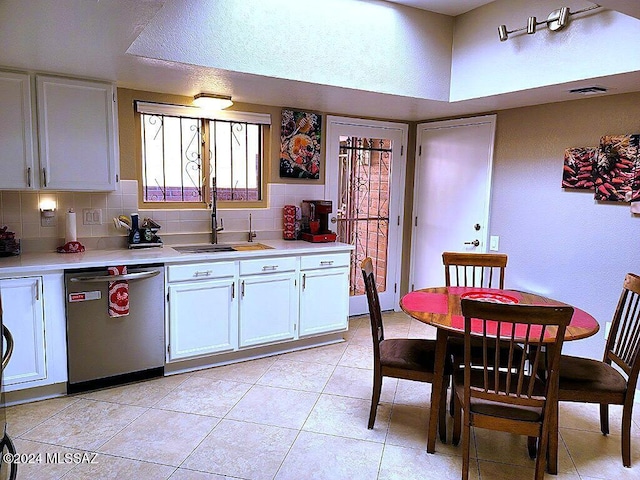 kitchen featuring sink, light tile patterned floors, stainless steel dishwasher, white cabinets, and tasteful backsplash