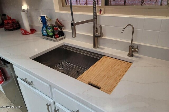 interior details with tasteful backsplash, sink, and light stone counters