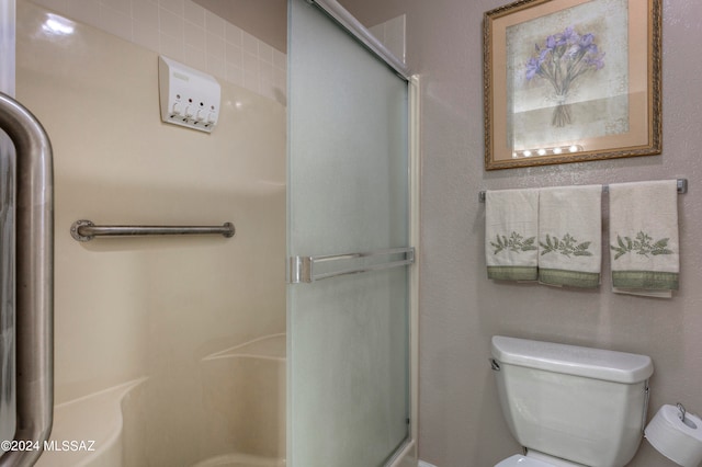 bathroom featuring a shower with shower door and toilet