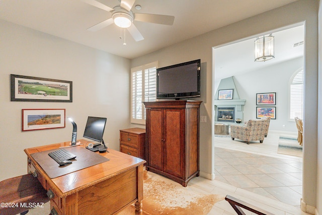 tiled office space with ceiling fan and a fireplace