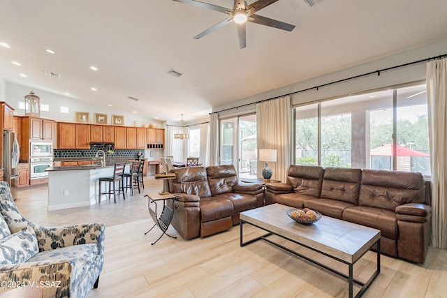 living room featuring ceiling fan, lofted ceiling, and sink