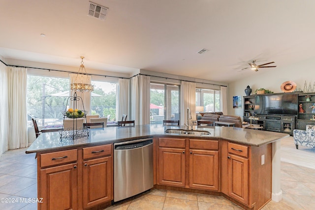 kitchen featuring ceiling fan with notable chandelier, a center island with sink, stainless steel dishwasher, and sink