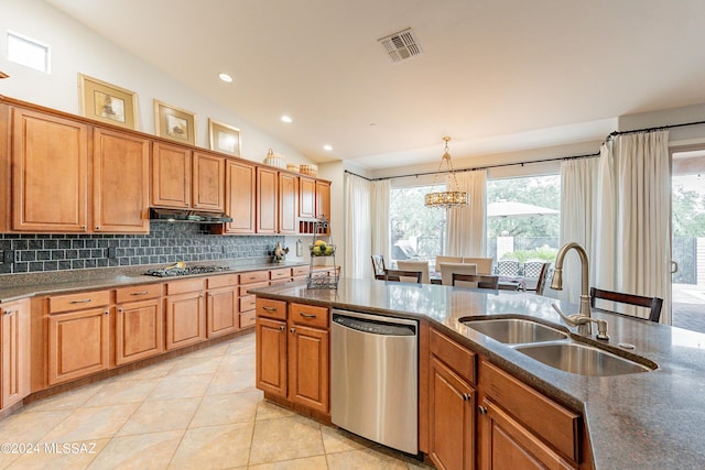 kitchen with appliances with stainless steel finishes, vaulted ceiling, sink, light tile patterned floors, and decorative light fixtures