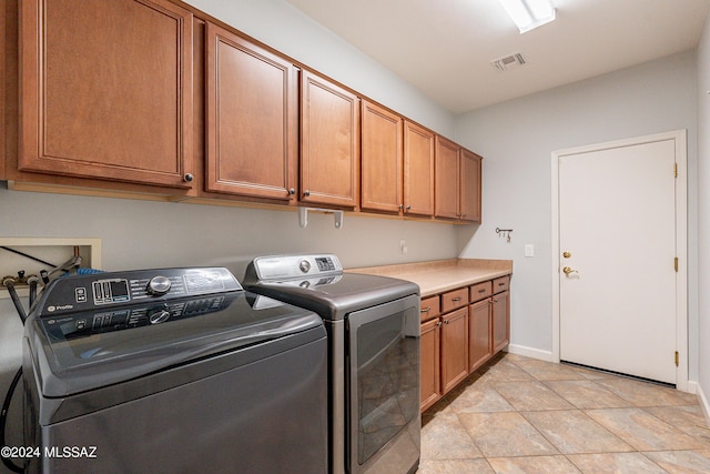 laundry area featuring cabinets, light tile patterned floors, and washer and dryer