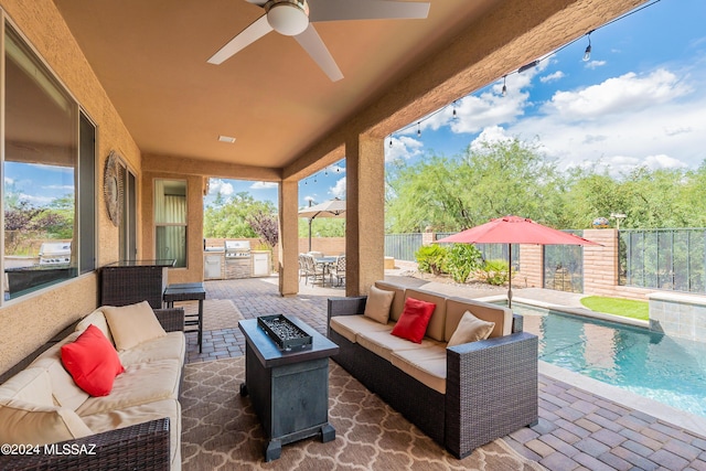 view of patio / terrace with grilling area, ceiling fan, an outdoor living space with a fire pit, and exterior kitchen